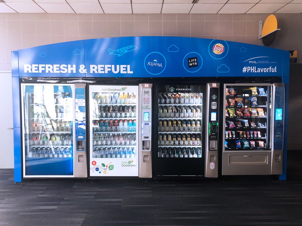 Four-machine vending enclosure with Refresh and Refuel graphics at Philadelphia International Airport